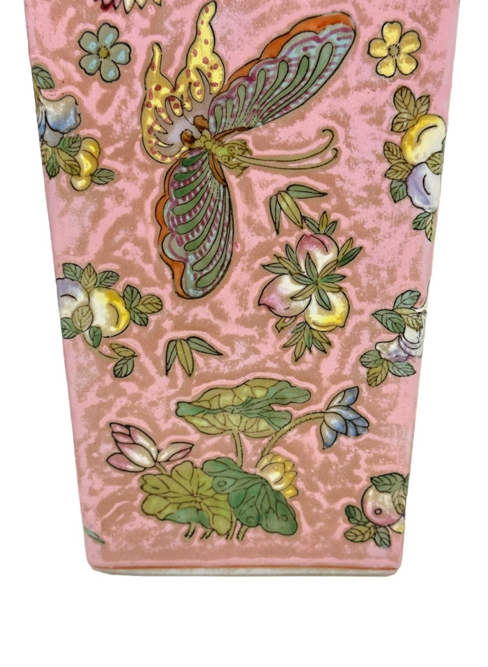 Close-up of vintage pink chinoiserie vases featuring intricate butterfly, fruit, and flower motifs.