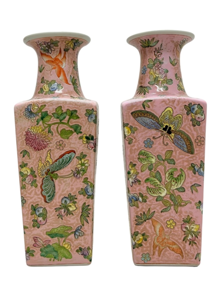 Close-up of vintage pink chinoiserie vases featuring intricate butterfly, fruit, and floral motifs.