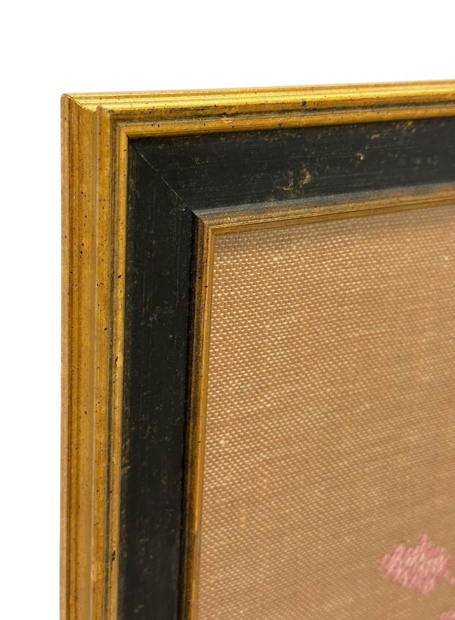 Close-up of vintage bird cross stitch art in black and gold frame.